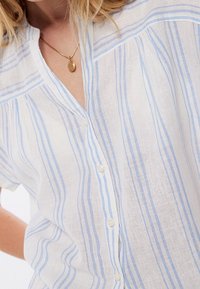 Chemise en lin à manches courtes, tissu blanc avec des rayures verticales bleues, col cranté et fermeture avant à boutons.