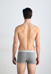 Boxer shorts gris avec une taille gris clair, en coton lisse, coupe ajustée, montrant un dos nu de derrière contre un fond neutre.