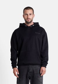 Felpa nera con cappuccio e tasca frontale, caratterizzata da un piccolo logo ricamato sul petto e bottoni a pressione sul collo.
