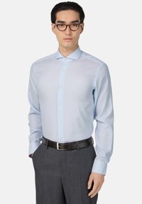 Camicia a righe azzurro chiaro con colletto button-down, maniche lunghe e una consistenza liscia, abbinata a pantaloni grigio scuro e una cintura nera.
