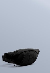 Svart vadderad midjeväska med en texturerad yta och justerbar rem. Har en slank, böjd form för en strömlinjeformad look.