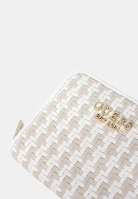 Borsa clutch intrecciata in beige e bianco, con una finitura lucida. Accenti in hardware dorato con il nome del marchio "GUESS" in evidenza.