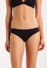 Black bikini briefs with a smooth, stretchy fabric. Low-rise design with a wide, comfortable waistband featuring a subtle logo.