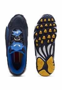 Laivastonsininen ja sininen lenkkari, jossa on lintu- ja siili-muotoisia nauhakoristeita, monivärinen sisäpohja ja keltamustat pohjat, joissa on teksturoitu pito ja Puma-logo.