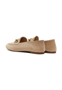 Beige Wildleder Slipper mit niedrigem Absatz, ausgestattet mit einem dekorativen goldenen Akzent auf dem Blatt und glatter Textur. Klassisches Slip-On-Design.