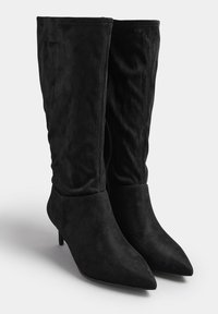 Stivali alti fino al ginocchio in suede nero con punta affusolata, tacco sottile e design morbido. Presentano una texture liscia e accenti minimi.