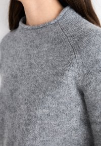 Harmaa villapaita, jossa korkea kaulus, resorineulottu pinta ja saumattomat olkapäät, korostaen pehmeää, kevyt painoinen designia.