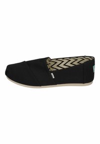 Scarpe slip-on in tela nera con punta arrotondata, presentano una fodera interna a motivo chevron e una suola in gomma beige.