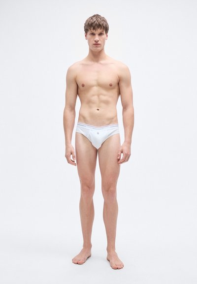 Άσπρα βαμβακερά εσώρουχα με χαμηλή μέση, διαθέτουν μια μαλακή ζώνη μέσης με λογότυπο. Ομαλή υφή και μινιμαλιστικό στυλ.