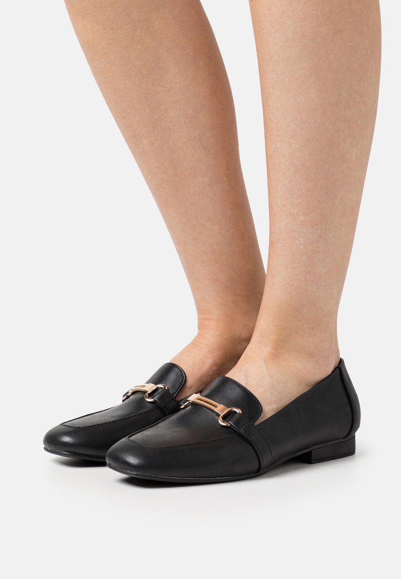 Černé loafers vyrobené z hladké kůže, s nízkým podpatkem a zlatým akcentem na přední straně, s jednoduchým designem.