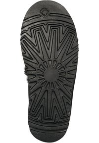 Zwarte rubberen schoenzool met een stervormig profiel, voorzien van ribbels, groeven en een circulair middendesign voor grip.