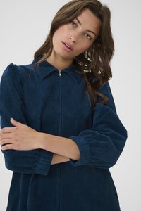 Navy-blaue Corduroykleid mit einem Reißverschluss, Kragen und voluminösen Ärmeln. Texturiertes Material mit vertikalen Rippdetails.