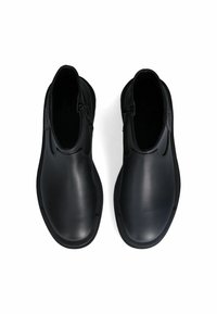 Stivali ankle in pelle nera con una texture liscia, chiusura con zip sul lato, punta tonda e suola piatta in gomma. Design minimalista senza marchi visibili.