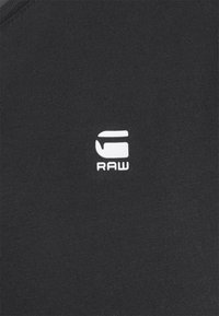 Tricou negru din bumbac cu un logo alb "RAW" pe piept. Materialul are o textură netedă și un guler rotund.