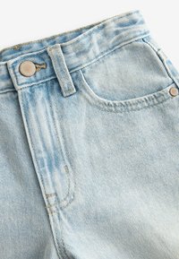 Jeans in denim blu chiaro con vita alta, dotati di tasca frontale, passanti per la cintura e un bottone metallico con leggeri segni di usura.