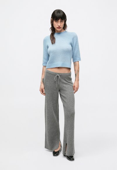 Pulover scurt tricotat bleu deschis cu mâneci scurte, asortat cu pantaloni gri cu talie largă, drepți, cu dungi verticale, cu deschideri laterale și talie cu șnur.