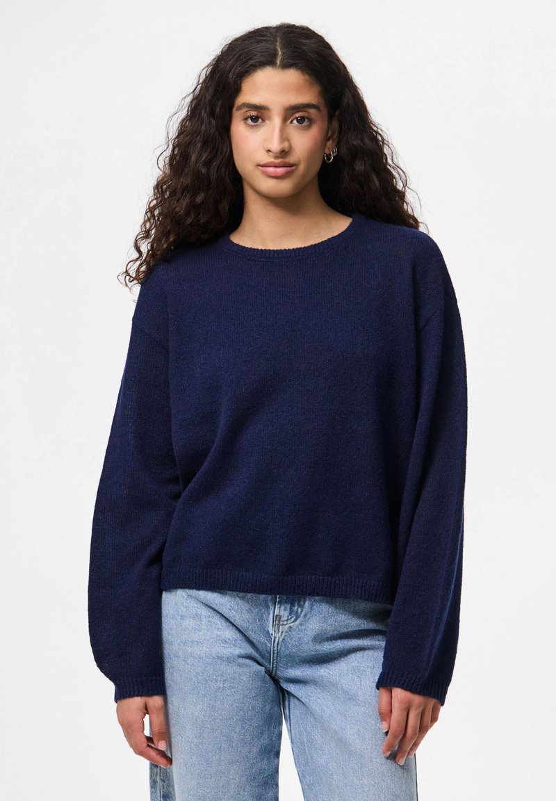 Suéter tricotado azul-marinho com decote redondo, mangas longas e design cropped. Textura macia e bainha e punhos canelados.