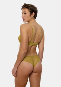 Ensemble de lingerie en dentelle vert olive avec un soutien-gorge à motifs, doté de fines bretelles et d'une fermeture à crochet, accompagné d'un string en dentelle assorti.