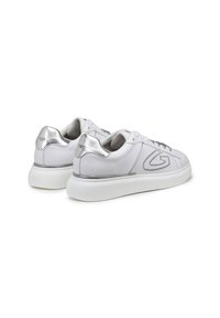 Sneakers bianchi in pelle con una texture liscia, dettagli argentati sul tallone e una robusta suola in gomma bianca. Design con lacci e dettaglio del logo.