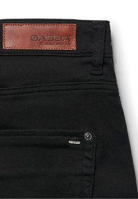 Melnas džinsu bikses ar ādas GABBA uzlīmi, kontrastējošām šuvēm un nelielu metāla logotipu priekšējā kabatā. Izturīgs džinsa materiāls.