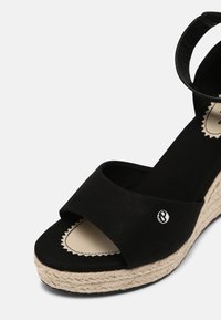 Sandale compensée noire à bout ouvert, bride de cheville et semelle plateforme en jute tressée.