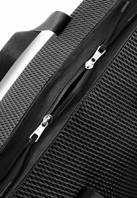 Schwarze Reißverschluss-Tasche aus strukturiertem Mesh-Material. Der Reißverschluss ist metallisch mit einem glatten Zug. Das Gesamtdesign ist rechteckig mit flachen Griffen.