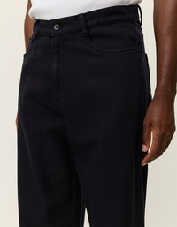 Μαύρο καμπάνα παντελόνι με ίσια γραμμή, διαθέτει κλείσιμο με κουμπί και τσέπες με σχισμές. Κατασκευασμένο από ανθεκτικό ύφασμα, με υφασμάτινη επιφάνεια.