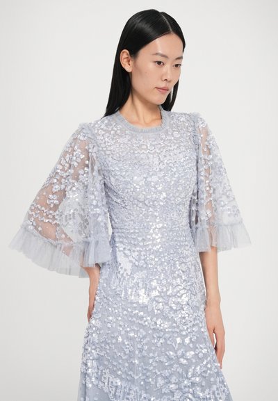Φόρεμα ανοιχτού γαλάζιου με παγιέτες και διαφανείς, βολάν μανίκια. Ο υφασμάτινος σχεδιασμός διαθέτει περίτεχνα λουλουδένια σχέδια και στρωμένα, ρέοντα υφάσματα.