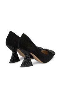Scarpe con tacco alto in suede nero con punta affusolata, decorate con accenti di cristallo sulla punta e tacco decorato con una forma unica.