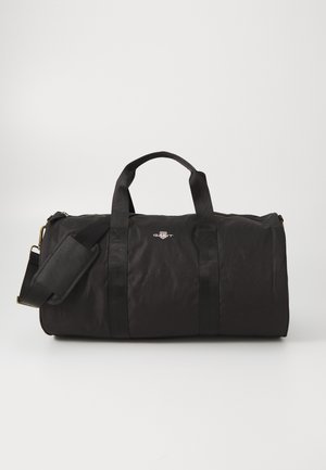 Borsa duffel nera realizzata in tessuto resistente, con due manici superiori, una tracolla regolabile e un dettaglio con logo frontale.