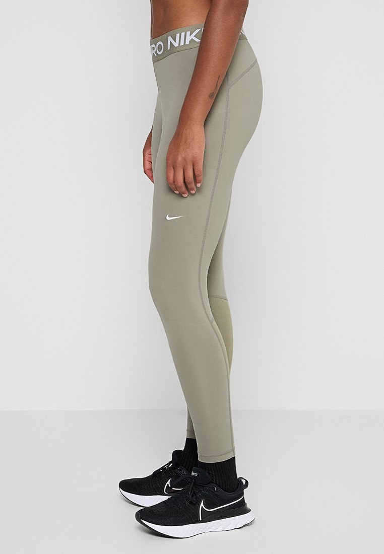 Leggings de cintura alta de Nike en verde olivo, hechos de una tela suave. Presentan un logo blanco en la pierna y una cinturilla de marca.