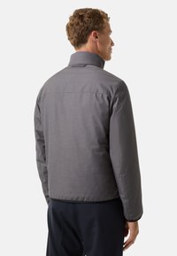 Grå, isoleret jakke med høj krave, der har en glat tekstur og et enkelt design, synlige syninger på skuldrene og ved manchetterne.