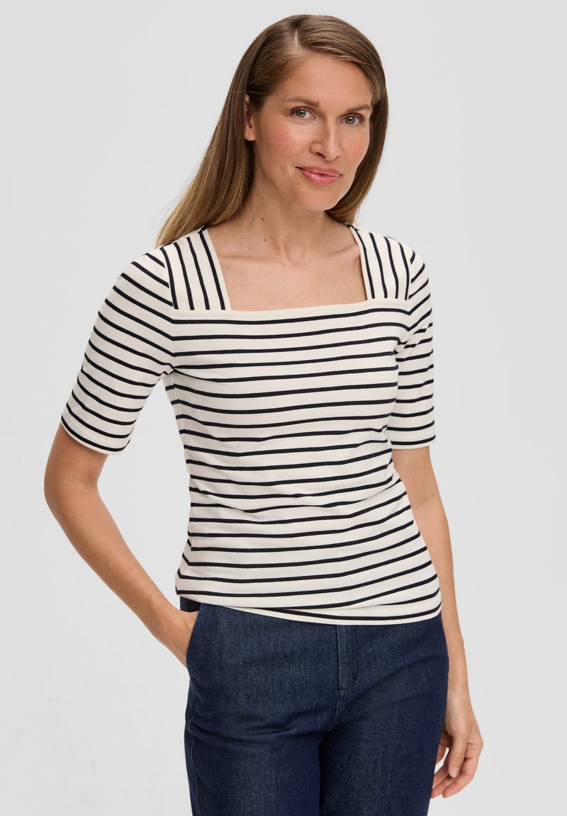 Gestreept t-shirt in crème en zwart, met een vierkante halslijn en korte mouwen. Zachte stof met een getailleerde pasvorm, gecombineerd met marineblauwe broek.