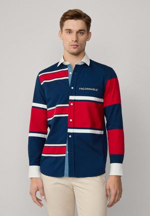 Camisa de manga larga con rayas horizontales en azul marino, rojo y blanco. Tela de algodón con un cuello azul claro en contraste. Logo de la marca en el frente.