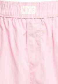 Shorts roses à rayures fines, taille élastique et étiquette NYC. Tissu doux avec une coupe décontractée et détails de poche latérale.