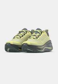 Αθλητικά παπούτσια ανοιχτού κίτρινου χρώματος με υφασμένη επάνω επιφάνεια, σκουρόγριζες λεπτομέρειες, παχιά ανατομική επένδυση και ελαστική σόλα με σχέδιο.