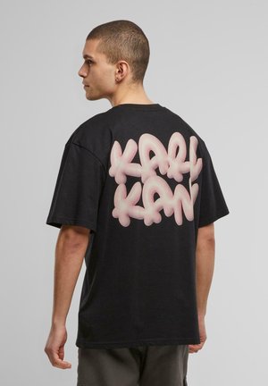 Black cotton t-shirt featuring a prominent pink graffiti-style logo "KARL KANI" on the back. Short sleeves and relaxed fit.