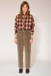 Chemise à carreaux dans des tons rouges et beiges, associée à un pantalon en velours côtelé vert olive. Coupe décontractée avec poignets retroussés. Mocassins marron complètent la tenue.