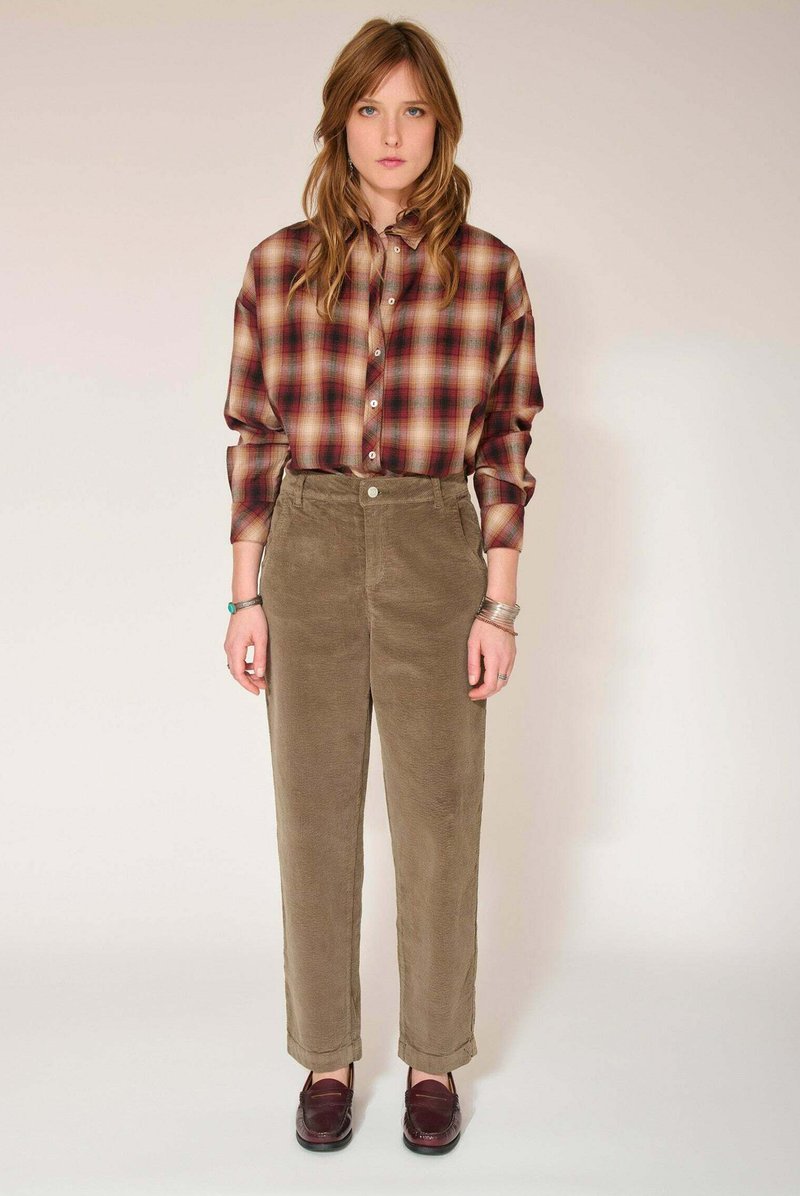Chemise à carreaux dans des tons rouges et beiges, associée à un pantalon en velours côtelé vert olive. Coupe décontractée avec poignets retroussés. Mocassins marron complètent la tenue.