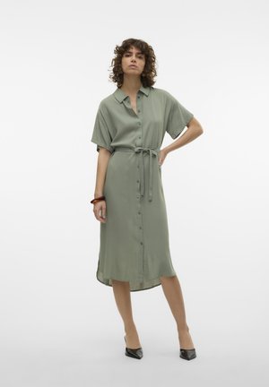 Vestito verde oliva con bottoni, maniche corte, cintura arricciata e orlo di lunghezza media. Tessuto liscio con una leggera lucentezza.
