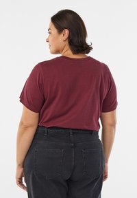 Bordo kratka majica z okroglim izrezom in sproščenim krojem. Kombinirana s črnimi hlačami z visokim pasom in zadnjimi žepi. Gladek tekstura.