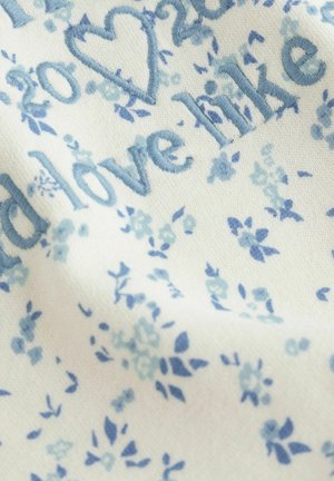 Tikitud kangas, millel on hele sinised lillemustrid kreemjal taustal ning tekstielemendid sarnastes sinistes toonides.