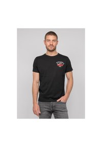 T-shirt en coton noir à manches courtes, avec un petit graphique blanc et rouge sur la partie gauche de la poitrine. Coupe standard, col côtelé.