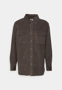 Bruine corduroy overhemd met lange mouwen, knoopsluiting aan de voorkant, twee borstzakken en een klassieke kraag; bevat subtiele strepen en logodetails.