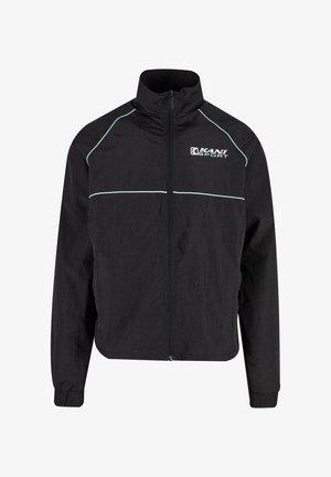 Melnā sporta žakete ar augstu apkakli, rāvējslēdzēju priekšā un gaiši zilu apdari. Izgatavota no viegla, teksturēta auduma.