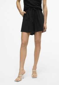 Pantaloni corti neri realizzati in tessuto leggero, con vita elastica, cordoncino e tasche laterali. Texture liscia con una vestibilità comoda.