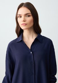 Navyblauw button-up shirt met een zachte, gestructureerde stof, een kraag en een relaxte pasvorm, voorzien van knopen aan de voorkant.