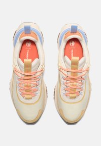 Sneakers med en beige tygöverdel, orange detaljer, blå bakdel och flerfärgade skosnören. Har en strukturerad sula och vadderad tunga.