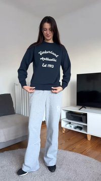 Tengerészkék pulóver fehér felirattal: "Timberland Authentic Est 1973," szürke melegítőnadrággal párosítva. Puha anyag, kényelmes szabás és letisztult dizájn.