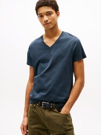 T-shirt bleu marine en coton avec col en v, associé à un pantalon vert olive. Présente un petit logo sur la poitrine et une coupe décontractée.